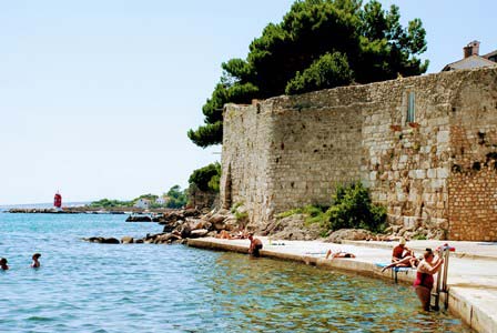 Bañito en piscinas naturales bajo las murallas romanas de Krk en Croacia